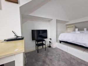 a bedroom with a bed and a flat screen tv at Nice Living Serviced Accommodations 9 (King-Size Studio Flat + Kitchen) in Coventry