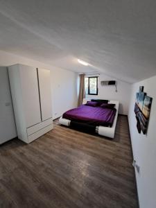 a bedroom with a purple bed and wooden floors at Casa 3 Catei Veseli in Seciu