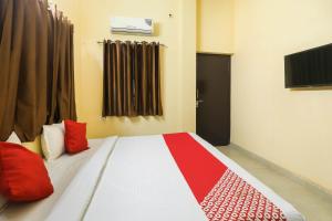 a bedroom with a bed with red pillows on it at OYO Flagship Laavin Inn Near Gomti Riverfront Park in Hasanganj