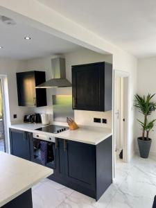 a kitchen with black cabinets and white counter tops at Modern bungalow in good location in Aberdulais