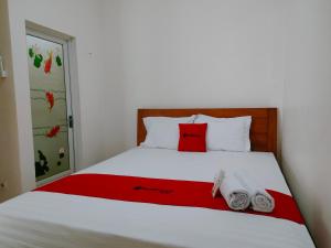 - un lit avec un oreiller rouge et des serviettes dans l'établissement RedDoorz Syariah near Jogja Expo Center, à Demangan