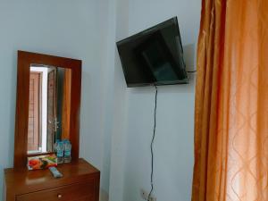 un téléviseur à écran plat accroché au mur à côté d'un miroir dans l'établissement RedDoorz Syariah near Jogja Expo Center, à Demangan