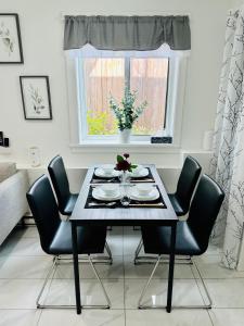 a dining room table with black chairs and a window at 2BR 1.5BA Full Kitchen Private Guest House - Free Parking - Central Location in Vancouver