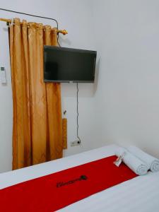 une chambre avec un lit avec une télévision à écran plat dans l'établissement RedDoorz Syariah near Jogja Expo Center, à Demangan 37 autres photos