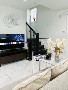 uma sala de estar com uma televisão e uma mesa em 2BR 1.5BA Full Kitchen Private Guest House - Free Parking - Central Location em Vancouver