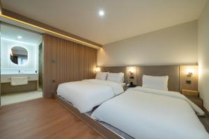 a bedroom with two beds and a bathroom with a mirror at Hound Hotel Gimhae Samgye in Gimhae