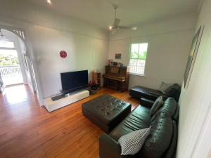 a living room with a leather couch and a flat screen tv at Neat, Tidy and Central in Brisbane