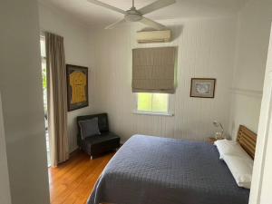 1 dormitorio con 1 cama, 1 silla y ventilador de techo en Neat, Tidy and Central, en Brisbane
