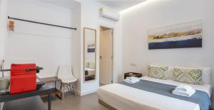 a white bedroom with a bed and a desk at Apartamentos Dolium in Seville