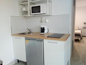 a white kitchen with a sink and a microwave at Finca Azahar Chipiona in Chipiona