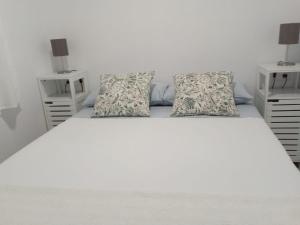 een slaapkamer met een wit bed en 2 nachtkastjes bij Finca Azahar Chipiona in Chipiona