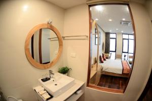Gia Le Hotel في تام داو: حمام مع حوض ومرآة وسرير