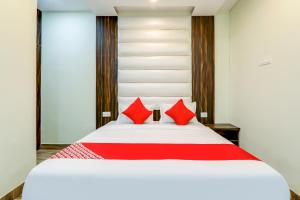 a bedroom with a large white bed with red pillows at 75217 Hotel Navya Grand in Gulzārbāgh