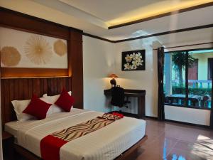 a bedroom with a bed with red pillows and a window at Lanta Riviera Resort - SHA Extra Plus in Ko Lanta