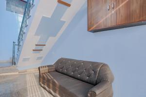 un sofá de cuero marrón en una habitación con escalera en SPOT ON Tomer Crown Palace, 