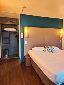 a bedroom with a large bed with a blue wall at Campanile Millau in Millau