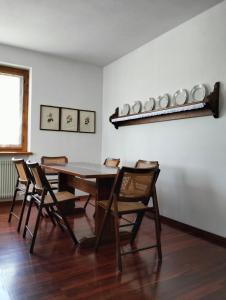 uma sala de jantar com uma mesa com cadeiras e pratos na parede em Vista mozzafiato sulle Dolomiti Friulane em Forni di Sopra