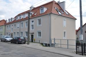 a white building with a red roof on a street at Apartament Wilenska in Mrągowo