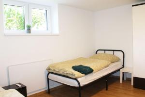 a bed sitting in a room with two windows at Ruhig gelegenes Apartment in Vaihingen an der Enz