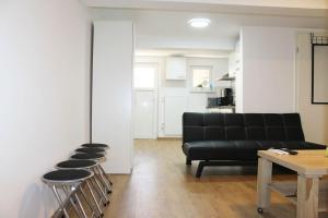 a living room with a black couch and stools at Ruhig gelegenes Apartment in Vaihingen an der Enz