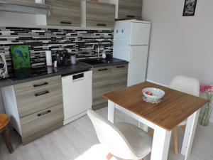 a kitchen with a wooden table and a white refrigerator at Arum in Codalet