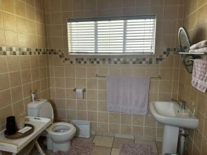 ein Badezimmer mit Toilette und Waschbecken in der Unterkunft Cozy Cottage Accommodation in Johannesburg in Roodepoort + 7 Fotos