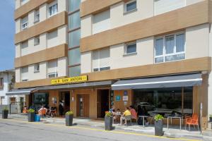 um edifício com pessoas sentadas em mesas à frente dele em Hotel Restaurante San Anton em Tapia de Casariego