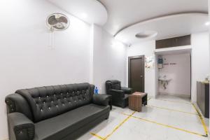 a living room with a black leather couch and a bathroom at Super OYO Capital O 78105 Hotel Figtree Premier in Patna