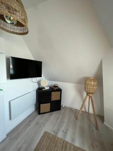 ein Wohnzimmer mit einem Flachbild-TV und einem Stuhl in der Unterkunft Le Nid de Chantal in Brienne-le-Château