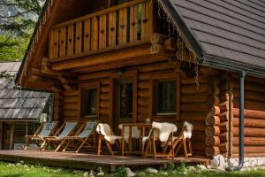 a cabin with chairs and a table on the porch at Pristava Lepena Village in Lepena