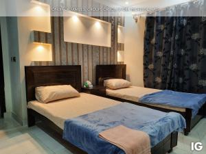 two beds in a hotel room with two bedsvisor at Spacious 3 Bedroom Furnished Family Home near Valencia Town, Lake City & Ring Road in Lahore