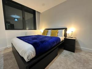 a bedroom with a bed with blue sheets and yellow pillows at 1 Bed Apartment near Old Trafford with free car park in Manchester