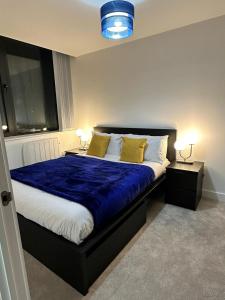 1 dormitorio con 1 cama con sábanas azules y almohadas amarillas en 1 Bed Apartment near Old Trafford with free car park, en Mánchester