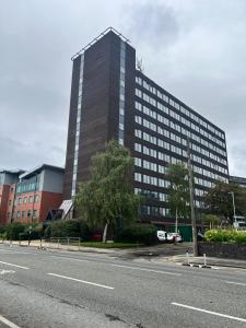 um edifício alto ao lado de uma estrada em 1 Bed Apartment near Old Trafford with free car park em Manchester