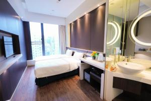 a bedroom with a bed and a sink and a mirror at Epoch Hotel in Hong Kong