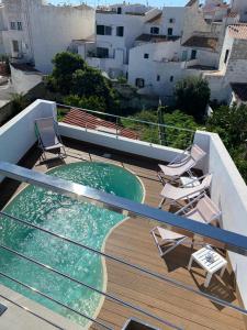 a deck with chairs and a swimming pool on a balcony at Casa S’Arraval in Mahón