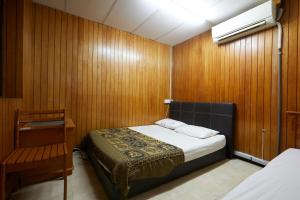 1 dormitorio con 1 cama y pared de madera en Ros Heritage Motel, en George Town