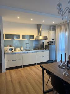 una cucina con armadi bianchi, un tavolo e una sala da pranzo di Ca’ Uccelli-Stupendo Appartamento 5 min da Venezia a Marghera