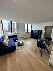 uma sala de estar com um sofá azul e uma mesa em 1 Bed Apartment near Old Trafford with free car park em Manchester