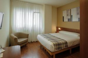 a hotel room with a bed and a chair at Hotel Restaurante San Anton in Tapia de Casariego