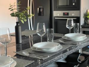 una mesa con platos y copas de vino. en Holdsworth House Apartments en Killingbeck