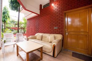 a living room with a couch and a brick wall at OYO Home Gautam Homestay in Dehradun