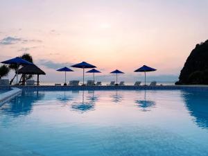 una piscina con sombrillas y sillas y el océano en Azana Essence Villa Tabitha Lombok en Bumbang