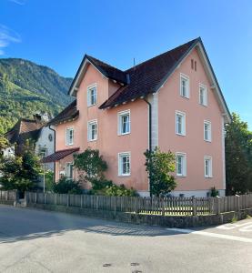 une maison rose avec une clôture sur le côté d'une rue dans l'établissement Stadthaus 1911, à Bludenz