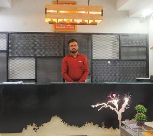 un hombre parado detrás de un mostrador en una habitación en Hotel Shree Meghdootam en Bhopal