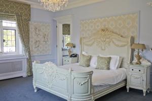 a bedroom with a white bed and a chandelier at Greenwoods Hotel & Spa in Stock