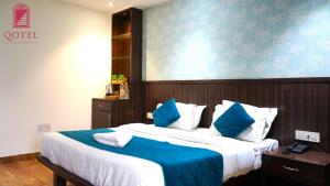 una camera da letto con un grande letto con cuscini blu e bianchi di Qotel B&B Hotel Rajouri Garden Above Ritu Marbel Near Rajouri Garden Metro Station a Nuova Delhi