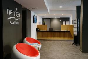una sala d'attesa con due sedie rosse e un bancone di Nemea Appart Hotel Coliseum Amiens Centre ad Amiens