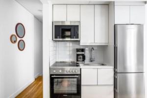 ニューヨークにあるRelaxing 3BR Apartmentのキッチン(白いキャビネット、ステンレス製の冷蔵庫付)