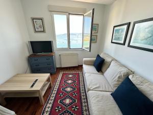 a living room with a white couch and a tv at Mar de Beluso in Bueu